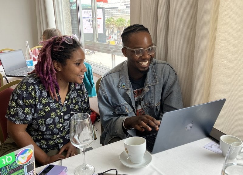 Dawn and Kudzayi sitting side by side in front of a laptop